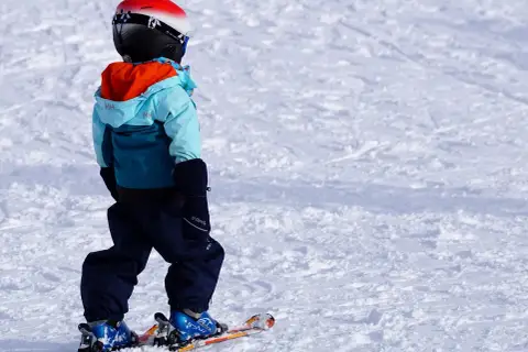 Bambino con casco, giacca e pantaloni da sci, pronto per sciare. Ecco cosa portare sulla neve per divertirsi in sicurezza!