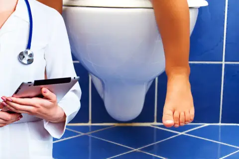 Medico con tablet osserva bambino sul water. Possibile problema di cacca bianca bambini.