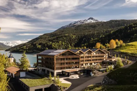 Das Gerstl Family Retreat, un hotel moderno con pannelli solari, si affaccia su un lago alpino e montagne boscose.